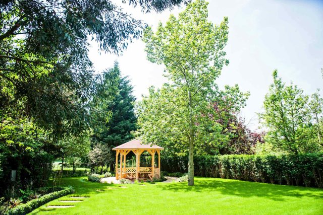 Large suburban garden desigened with York stone dining terrace and timber gazebo in north London, land drainage, lawn, dining terrace, heaters, planting.