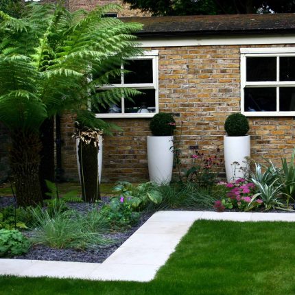 Modern Family Garden in Battersea with patio lighting planting and machined sandstone pathway specialist company stone work, planting herbaceous perennials.