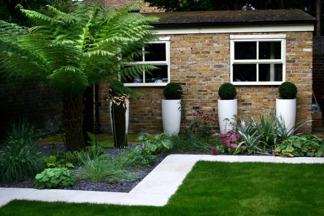 Modern Family Garden in Battersea with patio lighting planting and machined sandstone pathway specialist company stone work, planting herbaceous perennials.