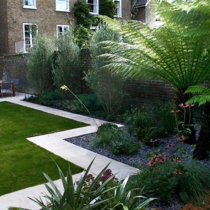 Modern Family Garden in Battersea with patio lighting planting and machined sandstone pathway specialist company stone work, planting herbaceous perennials.