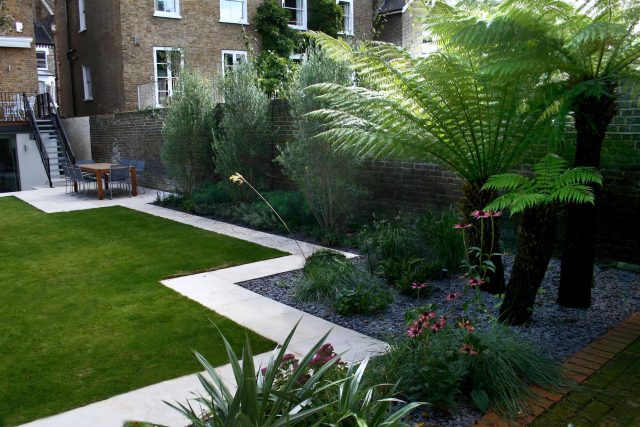 Modern Family Garden in Battersea with patio lighting planting and machined sandstone pathway specialist company stone work, planting herbaceous perennials.