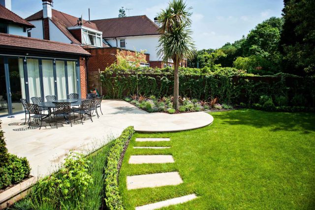 Large suburban garden desigened with York stone dining terrace and timber gazebo in north London, land drainage, lawn, dining terrace, heaters, planting.