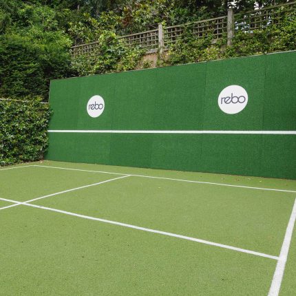 Large family garden design with outdoor kitchen, terrace, lighting, evergreens, lawn and stone-clad retaining wall designers specialist contractors in London.