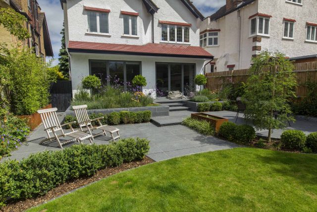 Family Garden, upper and lower stone terrance, wrapped with lawn, hidden trampoline Basalt terraces woodland planting Muswell Hill London design specialists.