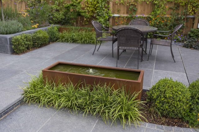 Family Garden, upper and lower stone terrance, wrapped with lawn, hidden trampoline Basalt terraces woodland planting Muswell Hill London design specialists.