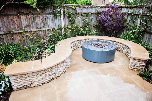 Family Garden with summer house in West London Feltham, curved seating bench, Charcoal Norstone tiered walling, specialist garden contractors horticulturists.