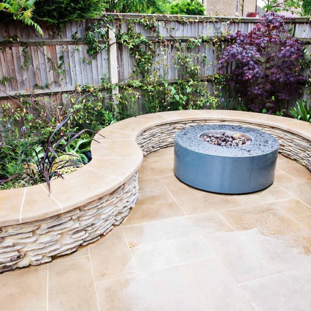 Family Garden with summer house in West London Feltham, curved seating bench, Charcoal Norstone tiered walling, specialist garden contractors horticulturists.