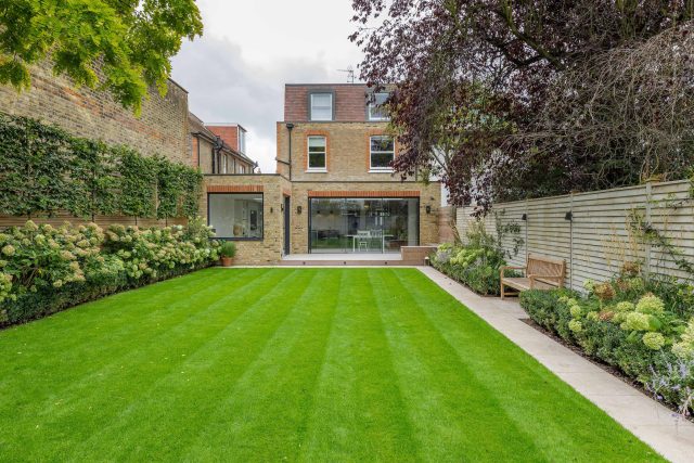 Family garden design in Barnes West London, lawn space as possible for various play activities and an intimate dining area with pleached Quercus Ilex trees.