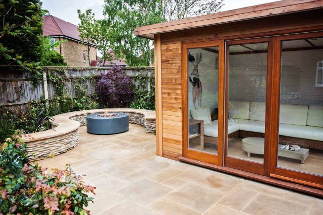 Family Garden with summer house in West London Feltham, curved seating bench, Charcoal Norstone tiered walling, specialist garden contractors horticulturists.