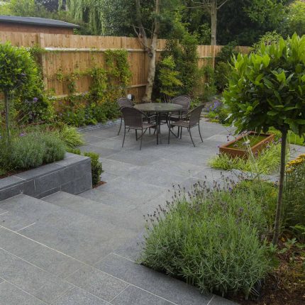 Family Garden, upper and lower stone terrance, wrapped with lawn, hidden trampoline Basalt terraces woodland planting Muswell Hill London design specialists.