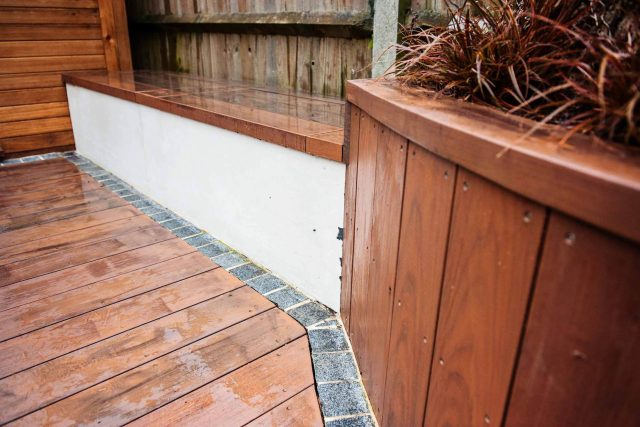 Family Garden with summer house in West London Feltham, curved seating bench, Charcoal Norstone tiered walling, specialist garden contractors horticulturists.