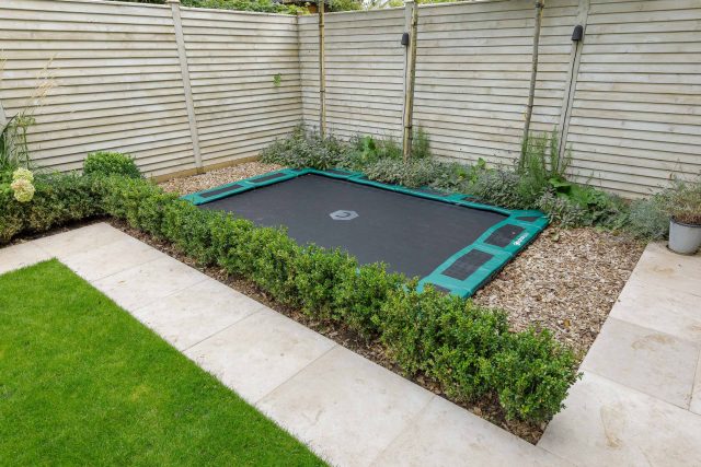 Family garden design in Barnes West London, lawn space as possible for various play activities and an intimate dining area with pleached Quercus Ilex trees.