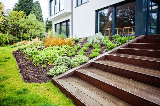 Farnham Garden Design Purbeck stone with multi-level Ipe hardwood decking, lawns and wild flower meadow and sculptural fire table Surrey landscaping.