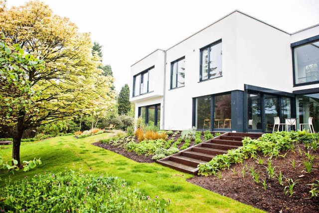 Farnham Garden Design Purbeck stone with multi-level Ipe hardwood decking, lawns and wild flower meadow and sculptural fire table Surrey landscaping.