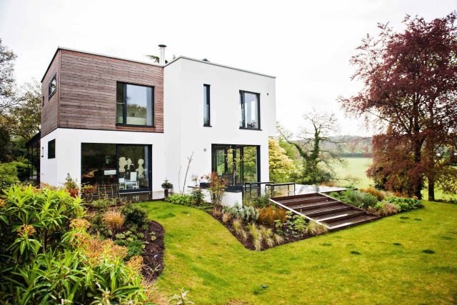 Farnham Garden Design Purbeck stone with multi-level Ipe hardwood decking, lawns and wild flower meadow and sculptural fire table Surrey landscaping.