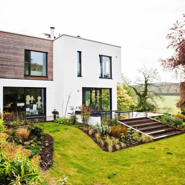 Farnham Garden Design Purbeck stone with multi-level Ipe hardwood decking, lawns and wild flower meadow and sculptural fire table Surrey landscaping.