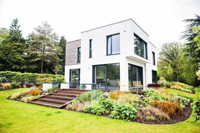 Farnham Garden Design Purbeck stone with multi-level Ipe hardwood decking, lawns and wild flower meadow and sculptural fire table Surrey landscaping.