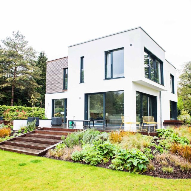 Farnham Garden Design Purbeck stone with multi-level Ipe hardwood decking, lawns and wild flower meadow and sculptural fire table Surrey landscaping.