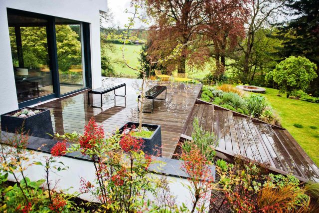 Farnham Garden Design Purbeck stone with multi-level Ipe hardwood decking, lawns and wild flower meadow and sculptural fire table Surrey landscaping.