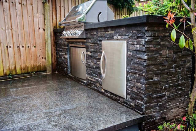 Family Garden with summer house in West London Feltham, curved seating bench, Charcoal Norstone tiered walling, specialist garden contractors horticulturists.