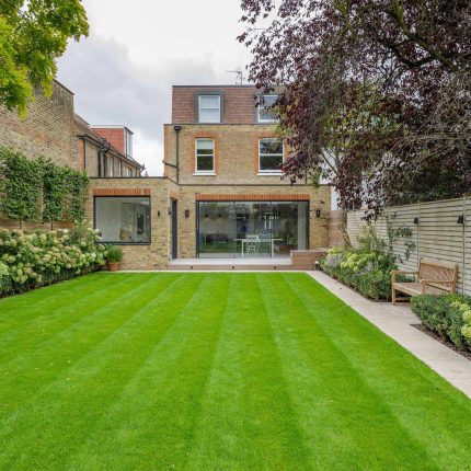 Family garden design in Barnes West London, lawn space as possible for various play activities and an intimate dining area with pleached Quercus Ilex trees.
