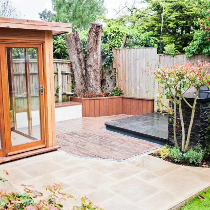 Family Garden with summer house in West London Feltham, curved seating bench, Charcoal Norstone tiered walling, specialist garden contractors horticulturists.