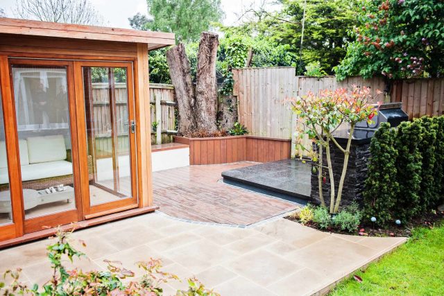 Family Garden with summer house in West London Feltham, curved seating bench, Charcoal Norstone tiered walling, specialist garden contractors horticulturists.