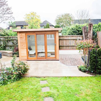 Family Garden with summer house in West London Feltham, curved seating bench, Charcoal Norstone tiered walling, specialist garden contractors horticulturists.