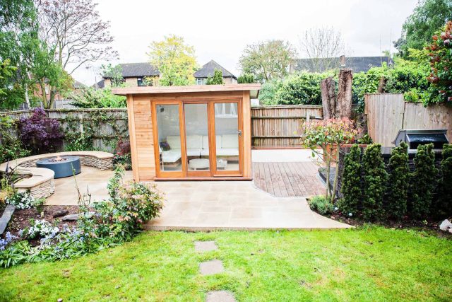 Family Garden with summer house in West London Feltham, curved seating bench, Charcoal Norstone tiered walling, specialist garden contractors horticulturists.